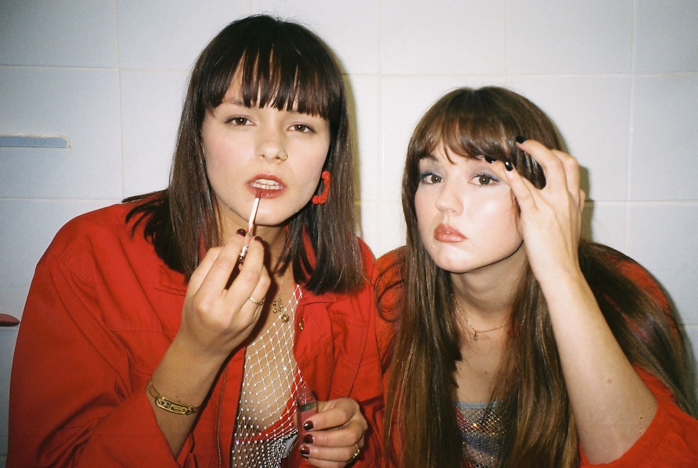 The duo Disgusting Sisters, one applying lipgloss & one applying eyeshadow